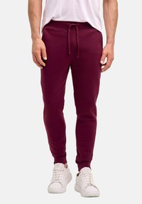 Bordeauxfarbene Jogginghose aus Baumwollmischung mit einem elastischen Bund und Kordelzug, gerippten Bündchen und glatter Textur. Weiße Sneakers sind im Lieferumfang enthalten.