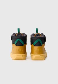 Barna bőr magas felső sportcipők, fekete hálós felsőrész, zöld részletekkel, párnázott szegéllyel és texturált gumitalppal. Tartalmaz egy tépőzáras pántot.