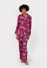 Lilla pyjamasæt med et mønster af sorte og hvide hunde. Toppen har krave og knapper; bukserne er løse med elastisk talje.