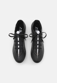 Baskets de sport noires avec un dessus texturé, lacets blancs et une bande blanche contrastante le long du centre. Présente un logo sur la languette.