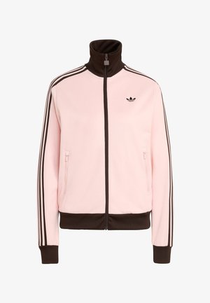 Roza trenirka z visokim ovratnikom, črnim zadrgo, kontrastnimi rjavimi trakovi in tremi črnimi črtami ob rokavih. Majhen logotip na prsih.