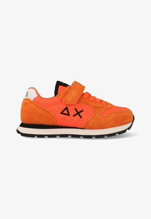 Heldere oranje sneaker met zwarte zool, zwarte driehoekige en X-vormige logo's aan de zijkant, oranje veters en een klittenbandsluiting bovenaan.