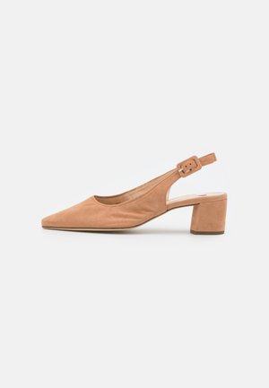 Zamszowy, beżowy but na obcasie typu slingback z cienkim paskiem z regulowaną klamrą, zakończony spiczastym noskiem, na białym tle.