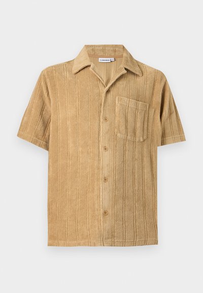 Chemise beige manches courtes à boutons, avec rayures verticales et une poche poitrine unique, présentant une texture douce en tissu éponge.