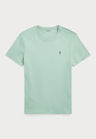 Piparmētru zaļa kokvilnas T-kreklu ar īsām piedurknēm, apaļu kakla izgriezumu un mazu zilu logo uz kreisās krūts. Gluda tekstūra un vienkāršs dizains.