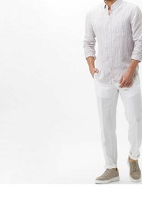 Jasnoszara, paskowana koszula z guzikami, zestawiona z białymi lnianymi spodniami i beżowymi sneakersami. Czyste linie, luźny fason, oddychający materiał.