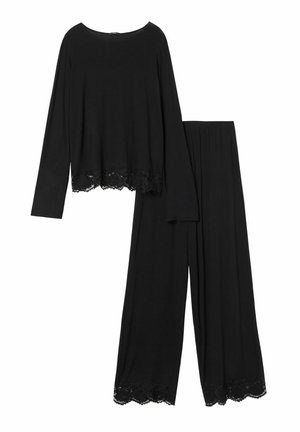 Top negro de manga larga con encaje en el dobladillo, combinado con pantalones anchos negros que también tienen detalles de encaje en los puños. Textura de tela suave.
