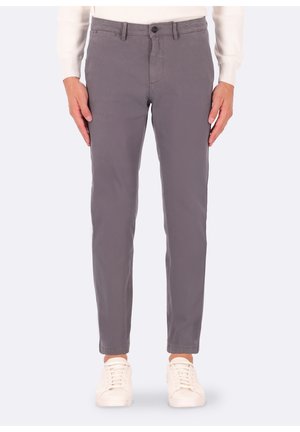 Chinos di cotone grigi con una vestibilità slim, dotati di chiusura con bottone frontale, tasche laterali e una texture liscia. Indossati con sneakers bianche.