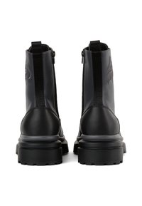 Botas negras de tobillo con un acabado brillante, presentando paneles laterales elásticos, cierres de cremallera y una suela gruesa texturizada para ofrecer agarre.