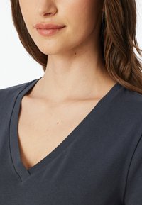 Dark gray v-neck t-shirt with short sleeves, soft cotton fabric, and subtle texture. Neckline features a smooth finish.