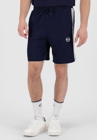 Marineblå idrettsshorts med hvite sidestiper og en logo på venstre ben. Elastisk midje med snor, laget av et glatt stoff.
