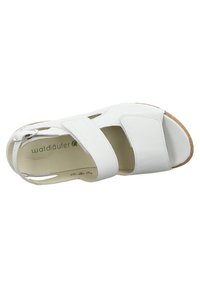 White leather sandal with adjustable strap, open-toe design, and textured cork sole. Features a cushioned footbed for comfort.
