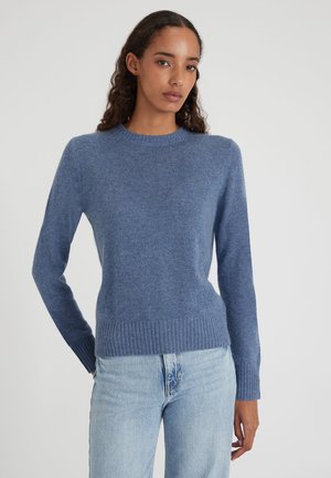 Blauer gestrickter Pullover mit Rundhalsausschnitt, langen Ärmeln und geripptem Saum. Weiche Textur und taillierter Schnitt, kombiniert mit hellblauen Jeans.
