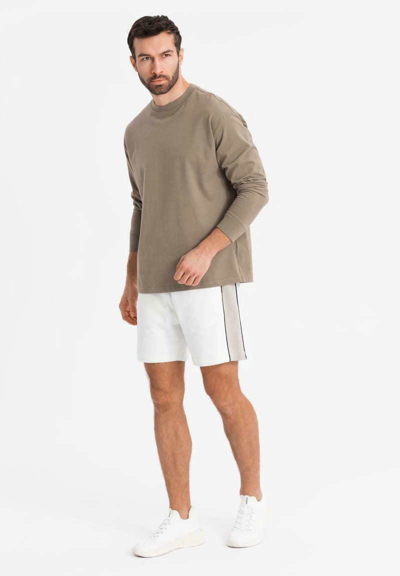 Kaki langærmet skjorte, hvide shorts med side sort stribe og hvide sneakers. Simpelt design uden synlige mønstre eller detaljer.