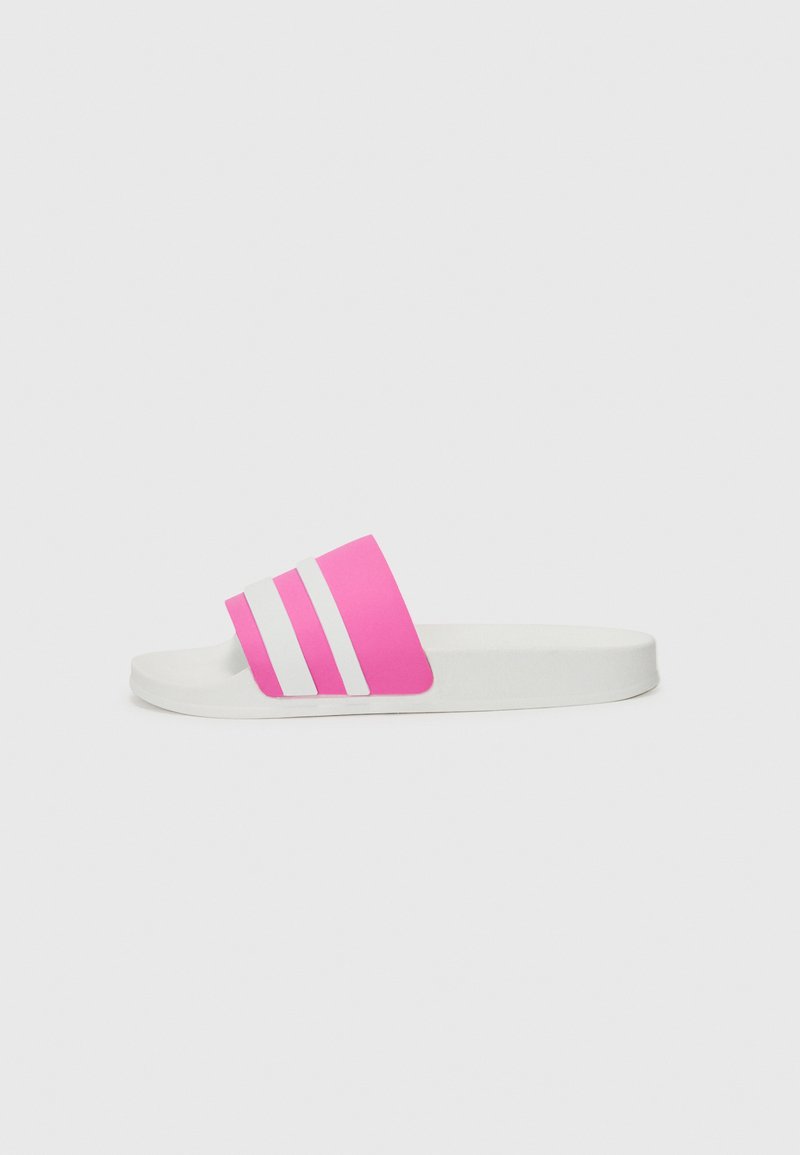 Pink slide sandal with white three-stripe design, a flat sole, and a soft upper material. Simple, minimalist shape with a smooth texture.