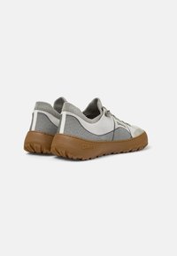 Light gray and beige sneakers with a textured design, rubber sole, and elastic knitted collar; detailed with subtle branding on the heel.