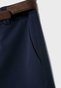Pantalon bleu marine avec détail de poche latérale et ceinture en suède marron contrastante à la taille.