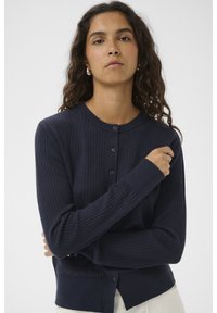 Marineblauer, gerippter Cardigan mit rundem Halsausschnitt, Knopfleiste und langen Ärmeln. Weiche Textur und figurbetontes Design mit einem Saum, der auf Taillenhöhe sitzt.