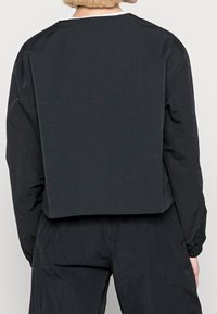 Svart croppad sweatshirt med en enkel rund halsringning och långa ärmar. Tillverkad av ett smidigt tyg, med minimal sömdetaljer.