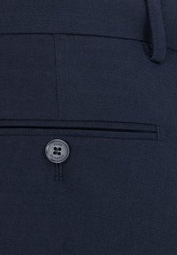 Granatowe spodnie z teksturowanej tkaniny, mała tylna kieszeń z czarnym guzikiem oraz wyszywany akcent nad kieszenią.