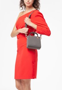 Borsa a tracolla grigia con texture, dalla forma strutturata, dotata di doppi manici e una tracolla rimovibile. Accenti in hardware color oro visibili.