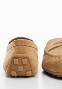 Vaaleanruskeat mokkanahka loafersit, joissa on pyöristetty kärki, tasapohja ja kumitassut pidon parantamiseksi. Yksinkertainen muotoilu, jossa on hienovarainen tikkaus.