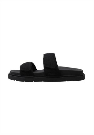 Sandalia plana negra con dos correas ajustables. Hecha de tela suave. Cuenta con una suela plana y un diseño minimalista. Textura ligera.