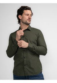 Camisa de manga larga abotonada en verde oscuro con patrón geométrico, que presenta un cuello, botones en el pecho y un acabado texturizado sutil.
