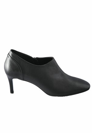Stivale alla caviglia in pelle nera con tacco, punta affusolata, texture liscia, dettaglio con zip sul retro e tacco sottile.