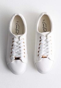 Sneakers bianchi in tela con punta tondeggiante, lacci piatti, occhielli in tono oro e accento metallico sulla linguetta. Superficie texturizzata, design minimalista.