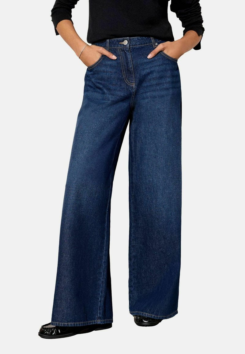 Široke plave traperice s gumbom, s dva prednja džepa i čistim završetkom. Imaju ravni kroj koji se proteže do članaka.