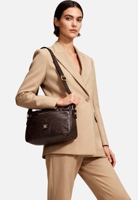 Borsa a mano in pelle marrone con finitura testurizzata, dettagli in oro e tracolla regolabile. Dotata di una tasca con zip e dettaglio con logo.