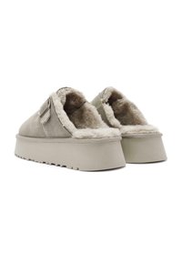 Scarpe slip-on in suede grigio chiaro, con una morbida fodera beige, suola spessa e piccolo dettaglio a strappo decorativo. Superficie testurizzata.