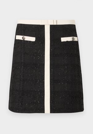 Mini-jupe noire texturée avec rayure verticale blanche et poches boutonnées assorties à bord blanc à l'avant, ainsi qu'une ceinture blanche.