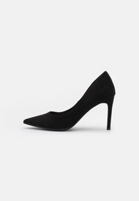 Zapato de tacón alto de ante negro con punta afilada y una silueta elegante. El tacón es esbelto y mide aproximadamente diez centímetros de altura.