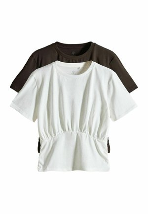 Twee katoenen T-shirts met korte mouwen, één witte met een geplooid detail in de taille aan de voorkant, gedragen over een effen donkerbruin T-shirt.