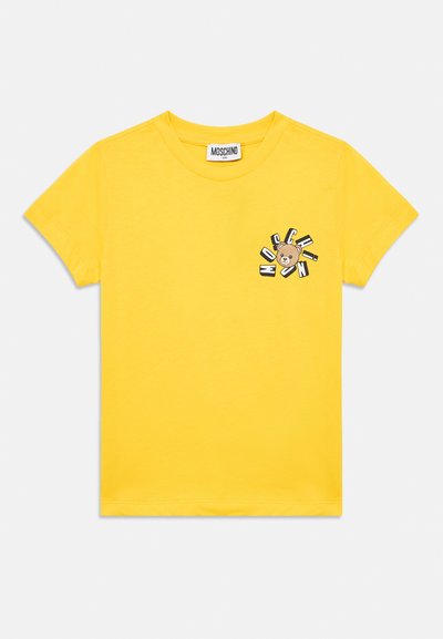 T-shirt jaune à manches courtes pour enfant avec col rond, comportant un petit motif d'ours et les lettres "MOSCHINO" sur la poitrine gauche.