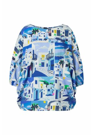 Blusa larga a maniche lunghe con stampa del villaggio mediterraneo blu e bianco, che mostra edifici bianchi, balconi, palme e strade di ciottoli.