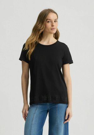 T-shirt noir à manches courtes avec un col rond, présentant un ourlet texturé et un motif subtil en bas. Tissu doux, coupe décontractée.