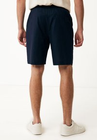 Marineblaue Shorts aus leichtem Stoff, mit elastischem Bund und Seitentaschen, von hinten gezeigt.