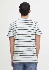 Kortermet t-skjorte i hvitt med marineblå horisontale striper, med rund hals og en avslappet passform. Stoffet ser mykt ut med minimal tekstur.