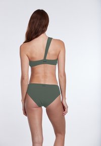 Grünes Bikini-Set mit einem trägerlosen Oberteil und klassischen Unterteilen. Hergestellt aus einem glatten, strukturierten Stoff mit minimaler Naht und Branding.