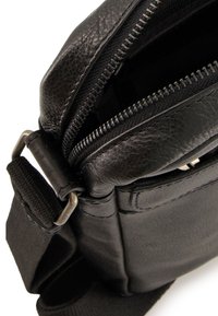 Sort læder messenger taske med lynlås åbning, sølv hardware og justerbar rem, med en tekstureret overflade og slankt design.