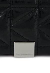 Borsa a tracolla nera trapuntata realizzata in materiale lucido, con hardware rettangolare argentato con inciso 'KARL LAGERFELD'. Motivo geometrico visibile.