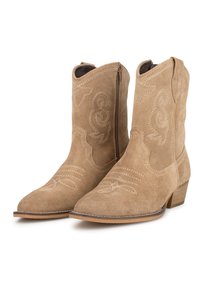 Botas de cowboy de ante en tono marrón claro con punta afilada, que presentan costuras decorativas y una cremallera lateral. El tacón bajo y apilado añade estabilidad.