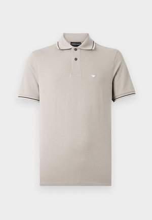 Light beige short-sleeve polo shirt with two black buttons, thin black and white stripes on collar and sleeve edges, and small logo on chest.