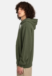 Oliven grøn hoodie med snoretræk i hætten, frontlomme og ribbede manchetter. Lavet af blødt stof, med en afslappet pasform og minimalistisk design.