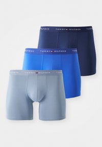 Trois paires de boxers de différentes teintes : gris clair, bleu et marine. Chacune comporte une ceinture élastique douce avec le logo "TOMMY HILFIGER".