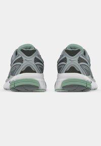 Γκρι και πράσινα αθλητικά παπούτσια με επάνω μέρος από δίχτυ και συνθετικό υλικό, επενδεδυμένο γιακά και λευκή ενδιάμεση σόλα με πράσινη λεπτομέρεια στη φτέρνα.
