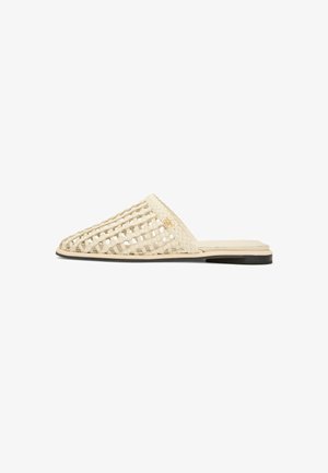 Beige vævet mule-slide med åbent gitterdesign, flad sål og let hæl i sort og beige lag.